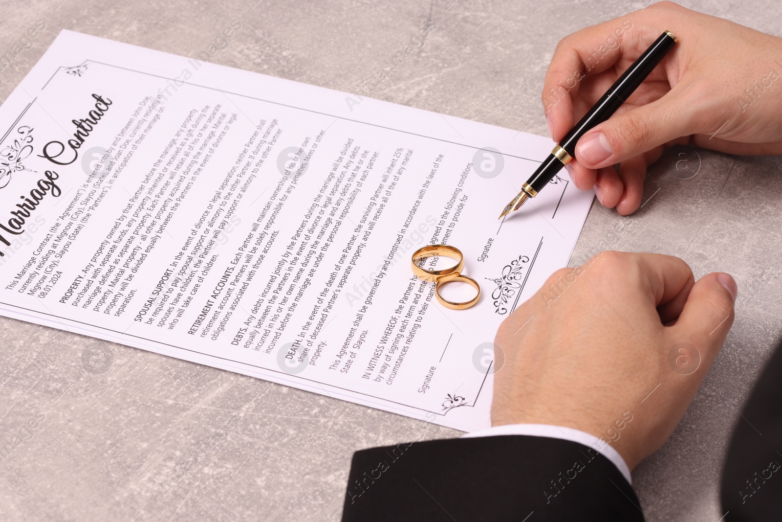 Photo of Man signing marriage contract at light grey table, closeup