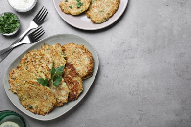 Photo of Delicious zucchini fritters served on grey table, flat lay. Space for text