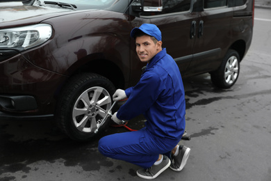 Worker changing car wheel at tire service