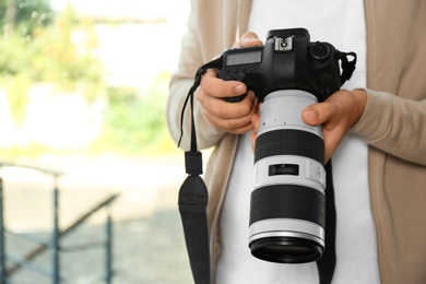 Photo of Male photographer with professional camera on blurred background. Space for text