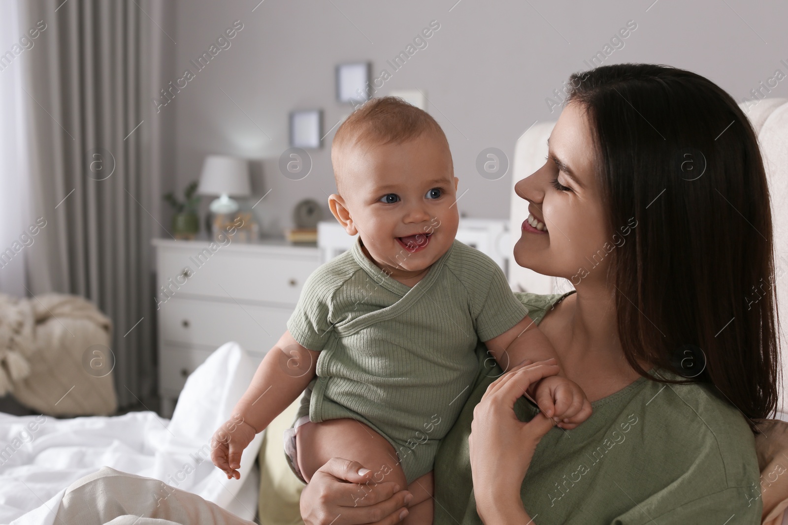 Photo of Happy young mother with her cute baby on bed at home