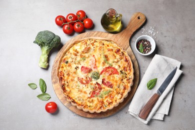 Photo of Tasty cheese quiche and ingredients on light grey table, flat lay