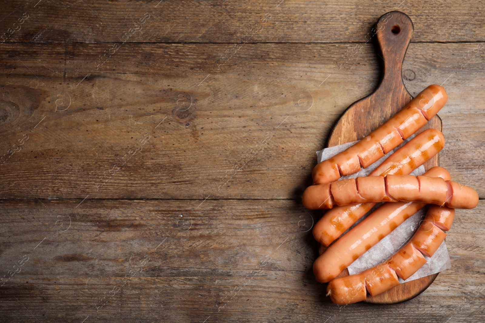 Photo of Delicious grilled sausages on wooden table, top view. Space for text