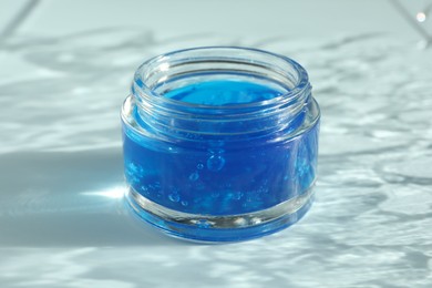 Photo of Open jar of cosmetic product on light blue background