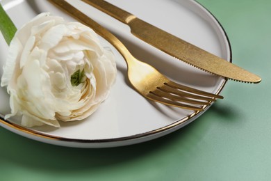 Photo of Stylish table setting with cutlery and flower on olive background, closeup