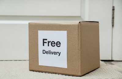 Parcel with sticker Free Delivery on rug indoors. Courier service