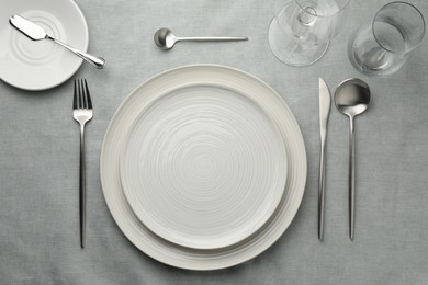 Photo of Stylish setting with cutlery, glasses and plates on grey table, flat lay