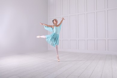 Photo of Beautifully dressed little ballerina dancing in studio. Space for text 