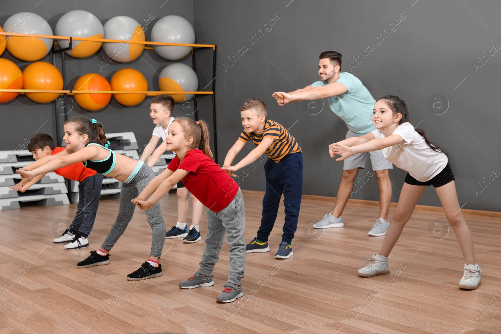 Photo of Cute little children and trainer doing physical exercise in school gym. Healthy lifestyle