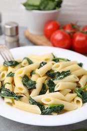 Photo of Tasty pasta with spinach on grey table, closeup