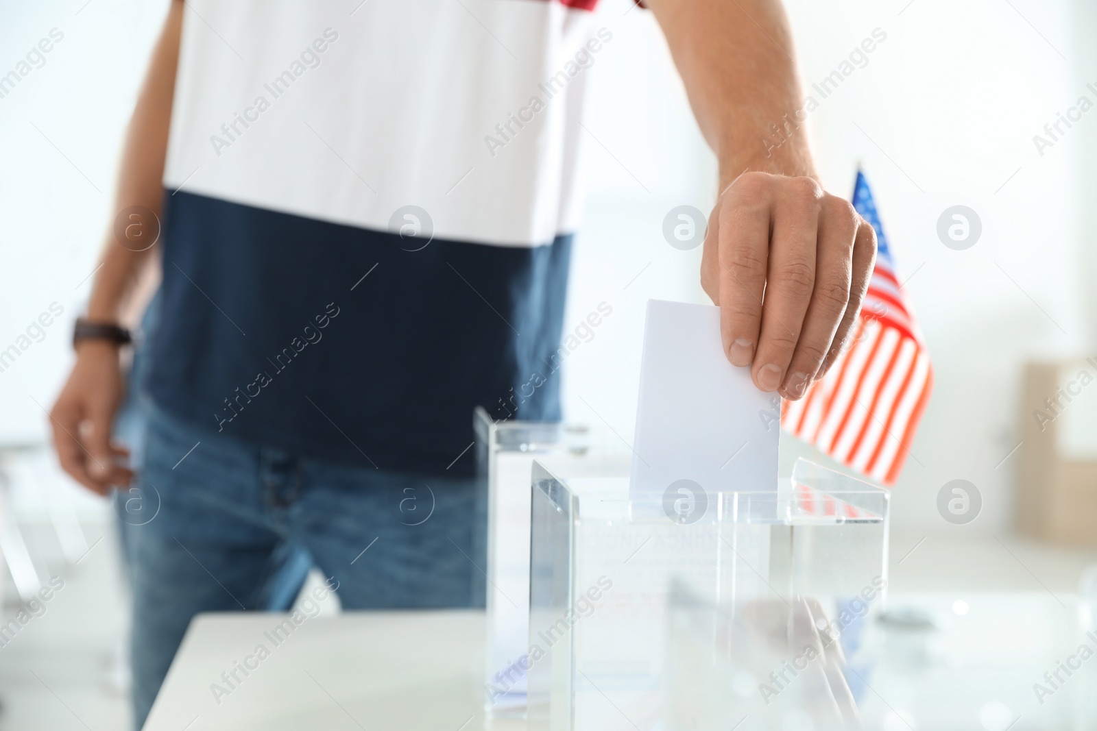 Photo of Man putting ballot paper into box at polling station, closeup