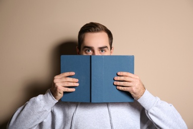 Photo of Young man with book on color background