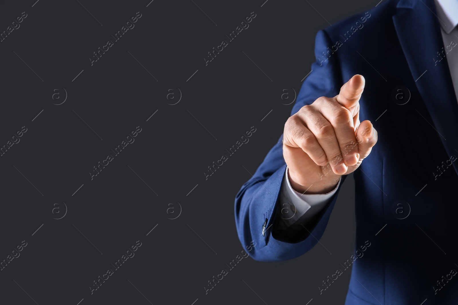 Photo of Businessman touching empty virtual screen against dark background, focus on hand