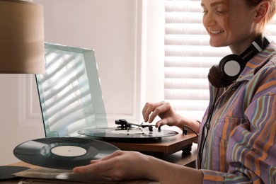 Beautiful young woman using turntable at home