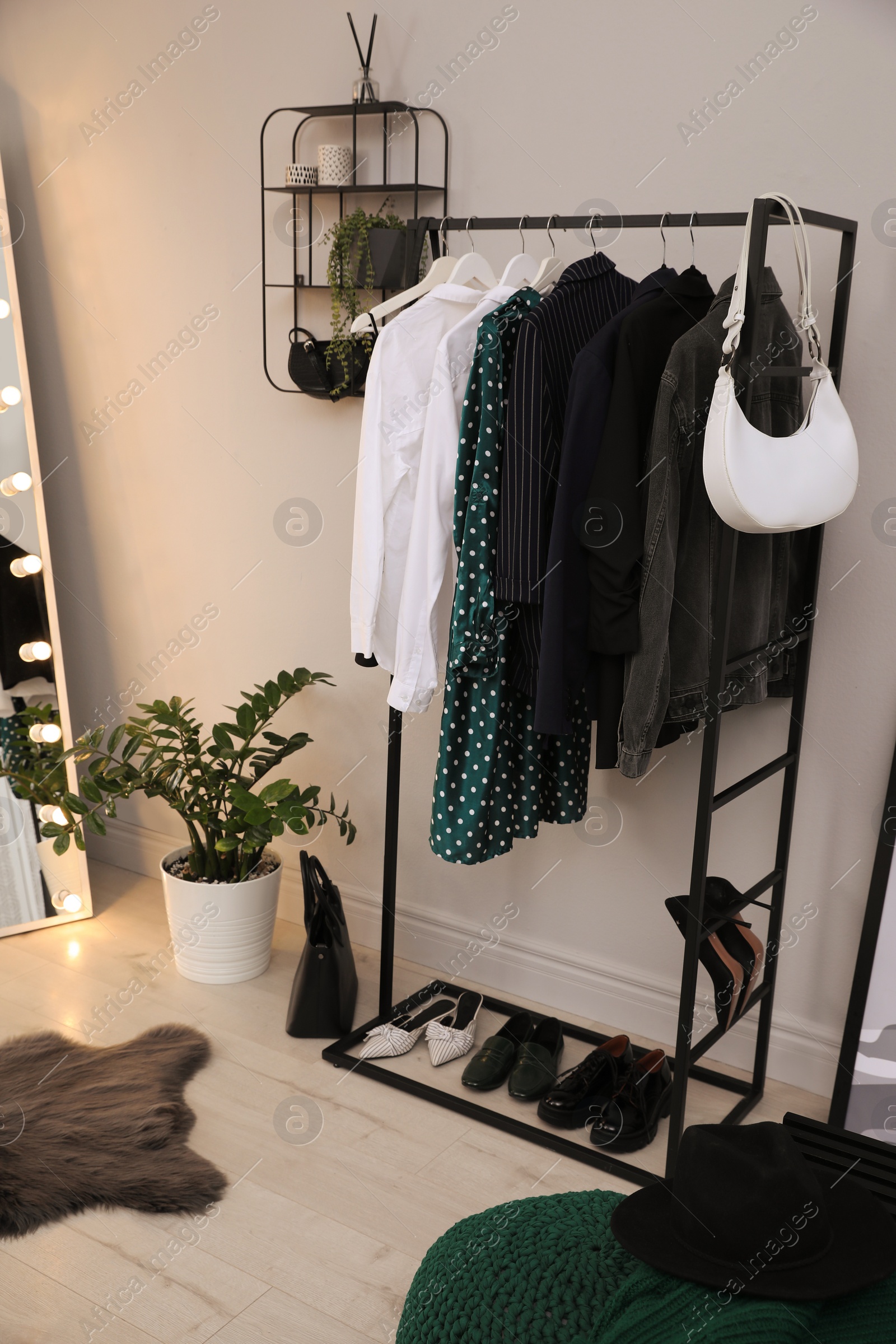 Photo of Rack with stylish women's clothes and shoes in dressing room