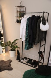 Rack with stylish women's clothes and shoes in dressing room