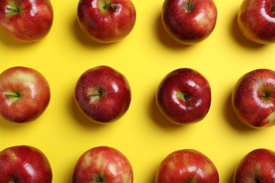 Tasty red apples on yellow background, flat lay