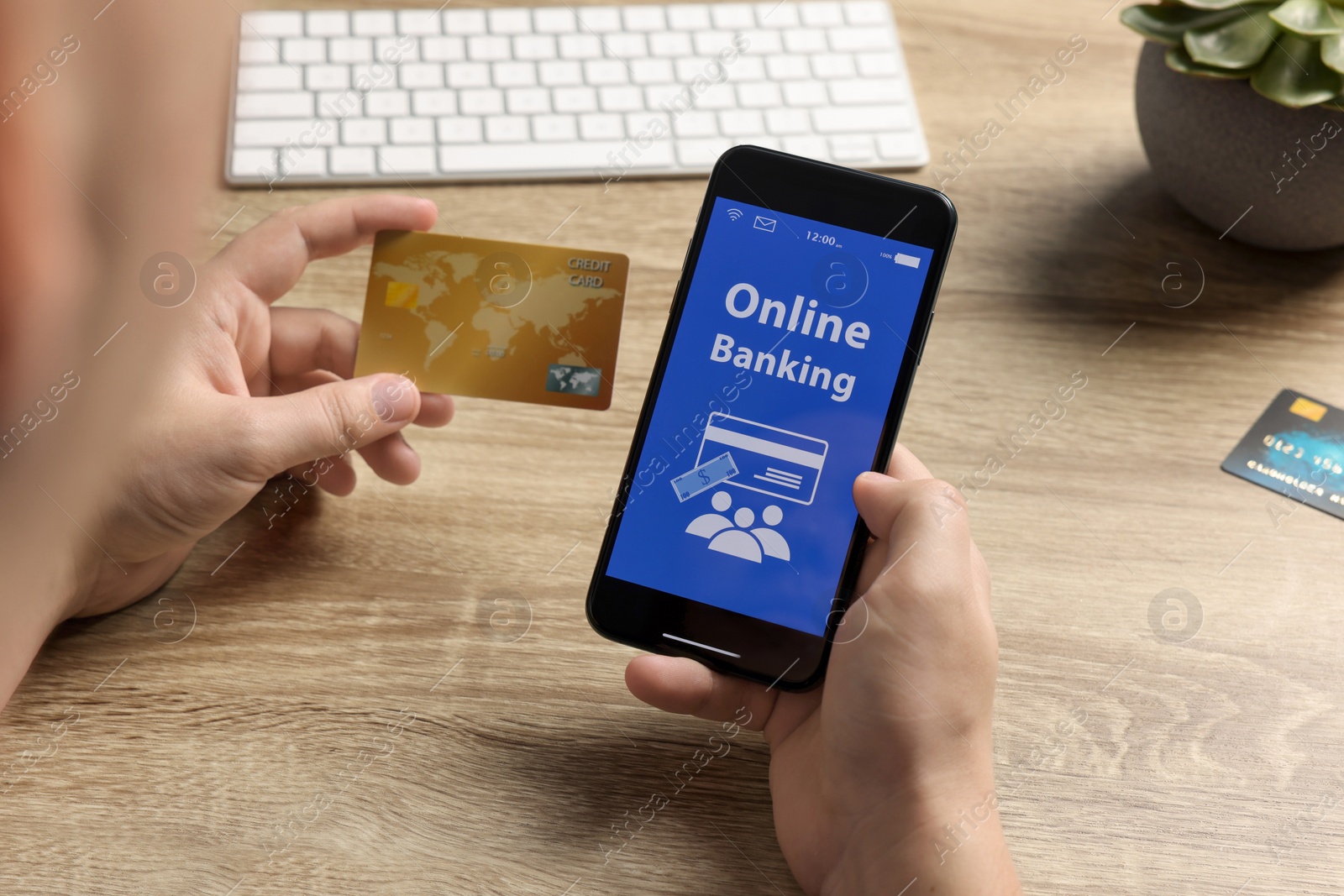 Photo of Man using online banking app on smartphone and credit card at wooden office table, closeup