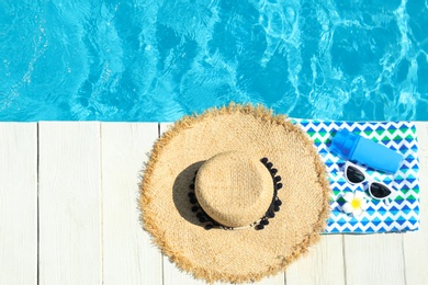 Flat lay composition with beach accessories on wooden deck near swimming pool. Space for text