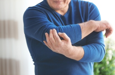 Photo of Mature man suffering from elbow pain at home