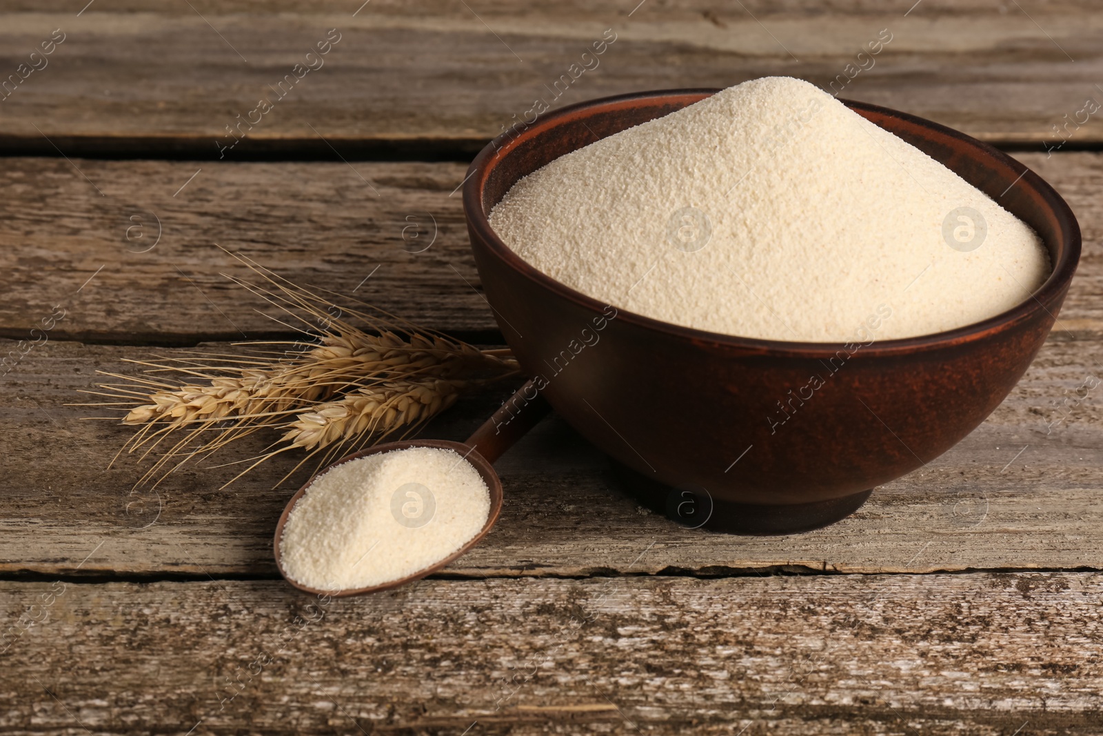 Photo of Semolina in bowl and spoon on wooden table