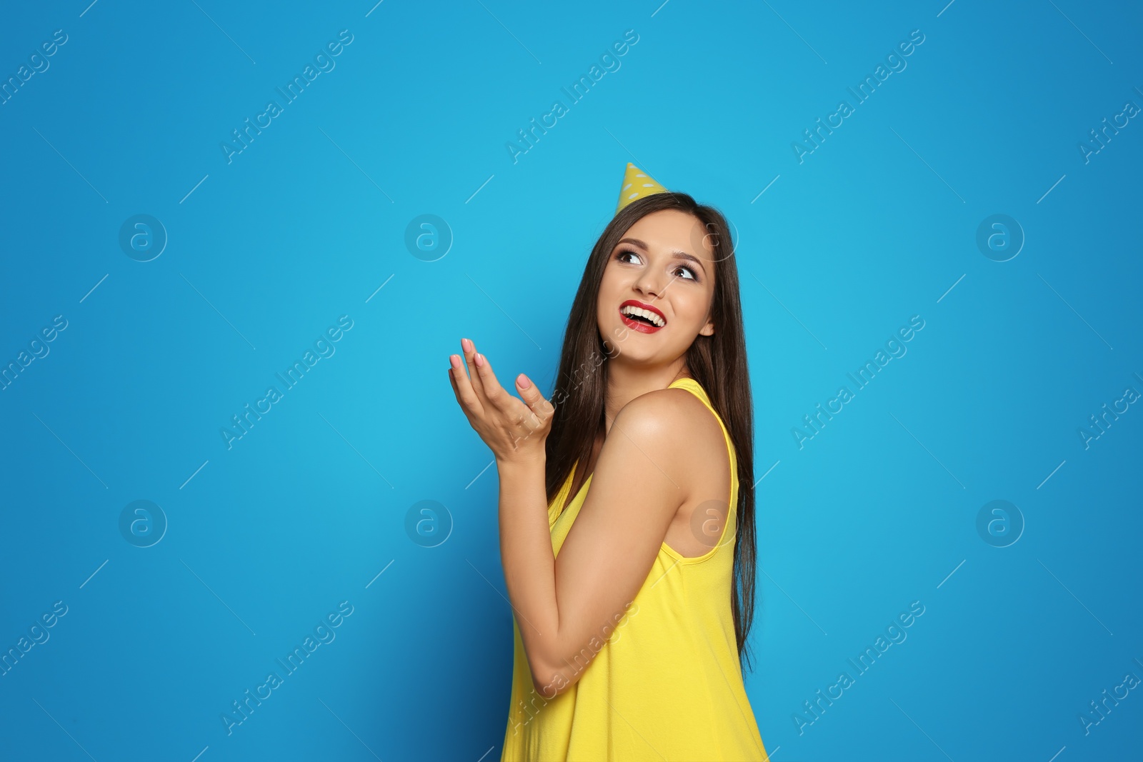 Photo of Young woman with party cap on color background. Birthday celebration