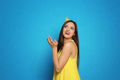 Young woman with party cap on color background. Birthday celebration