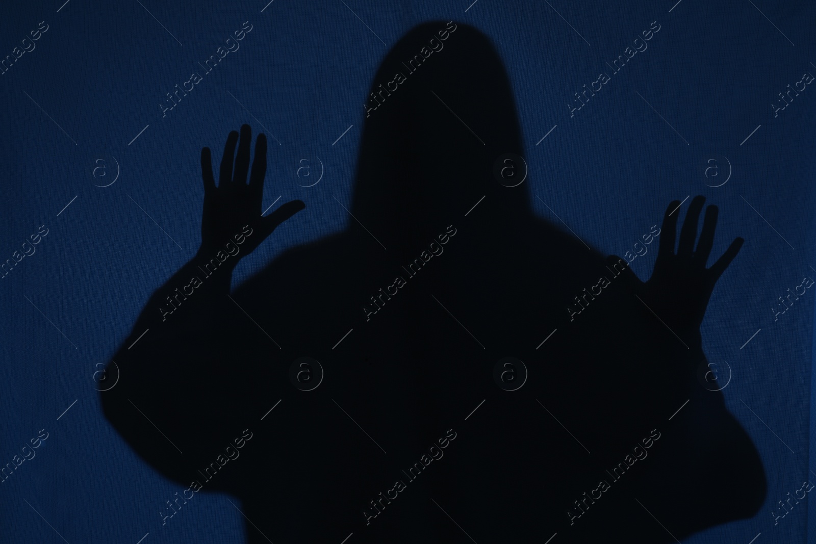 Photo of Silhouette of creepy ghost behind dark blue cloth