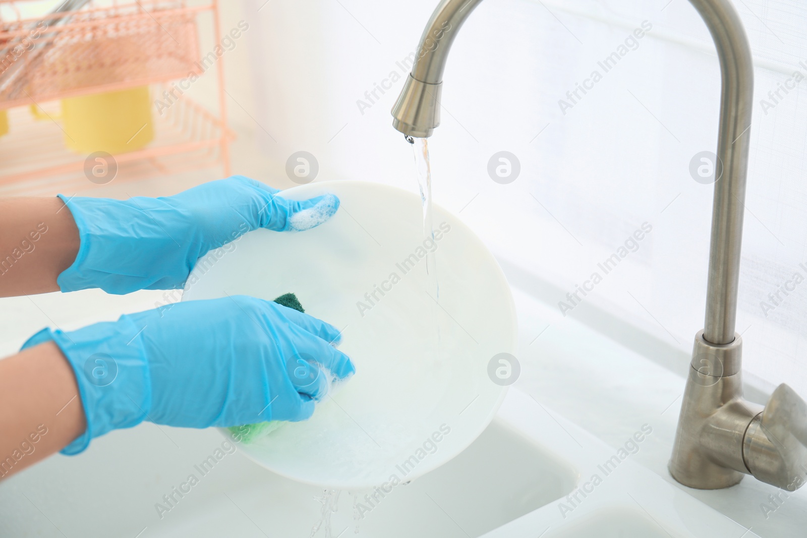 Photo of Woman washing ceramic plate in kitchen, closeup