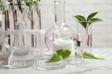 Photo of Organic cosmetic products, natural ingredients and laboratory glassware on white marble table