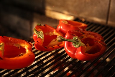 Photo of Cooking delicious fresh bell peppers on grilling grate in oven, closeup