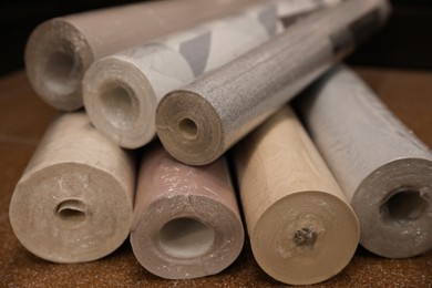 Photo of Different wall paper rolls on floor indoors, closeup
