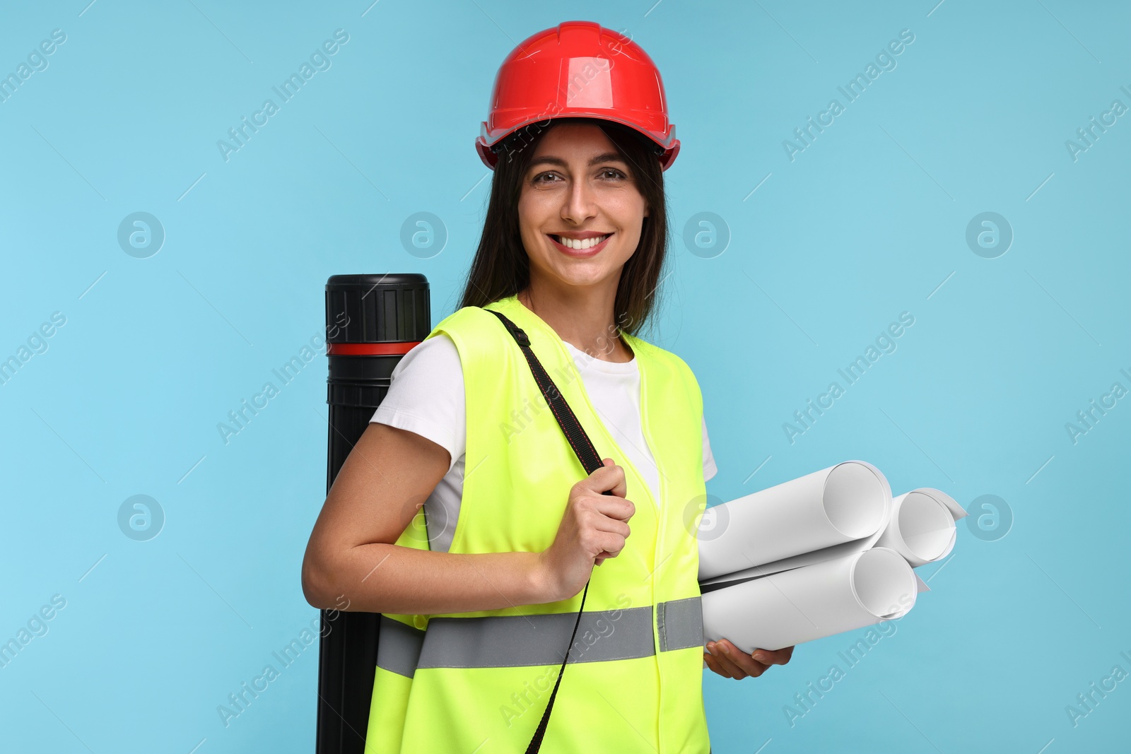 Photo of Architect in hard hat with drafts and tube on light blue background