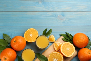 Photo of Delicious orange juice and fresh fruits on light blue wooden table, flat lay. Space for text