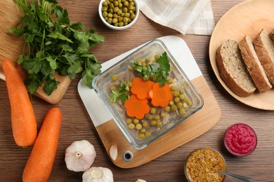 Photo of Delicious aspic with meat and ingredients on wooden table, flat lay