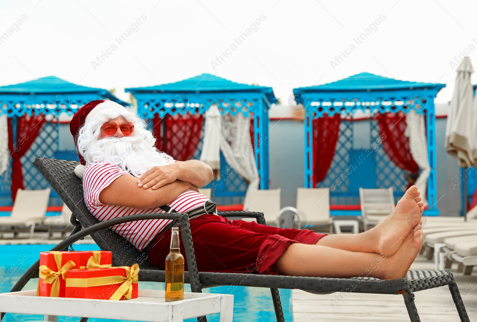 Photo of Authentic Santa Claus on lounge chair near pool at resort