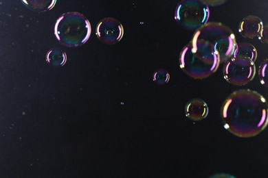 Photo of Beautiful transparent soap bubbles on dark background, space for text