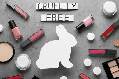 Photo of Flat lay composition with words Cruelty Free and different cosmetic products not tested on animals against light grey stone background
