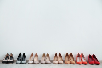 Photo of Collection of elegant shoes on floor at wall, space for text