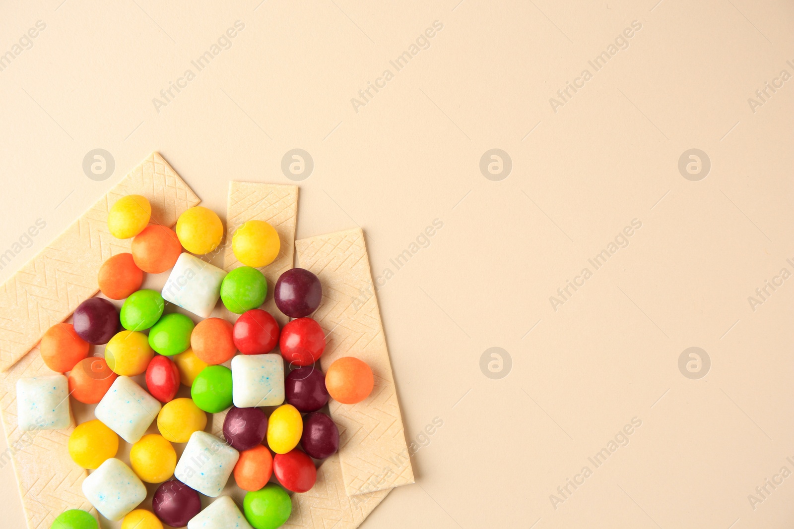 Photo of Different tasty chewing gums on beige background, flat lay. Space for text