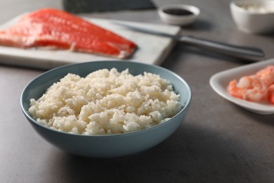 Cooked rice in bowl for sushi on grey table, closeup