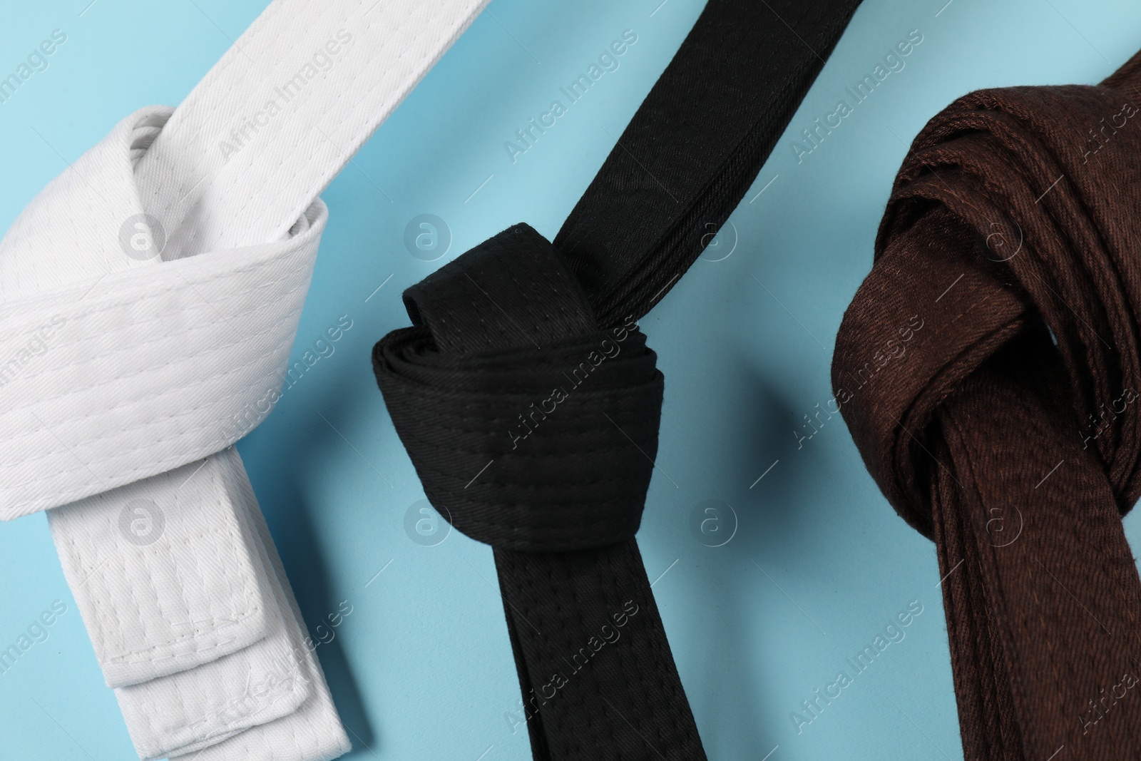 Photo of Karate belts on light blue background, flat lay