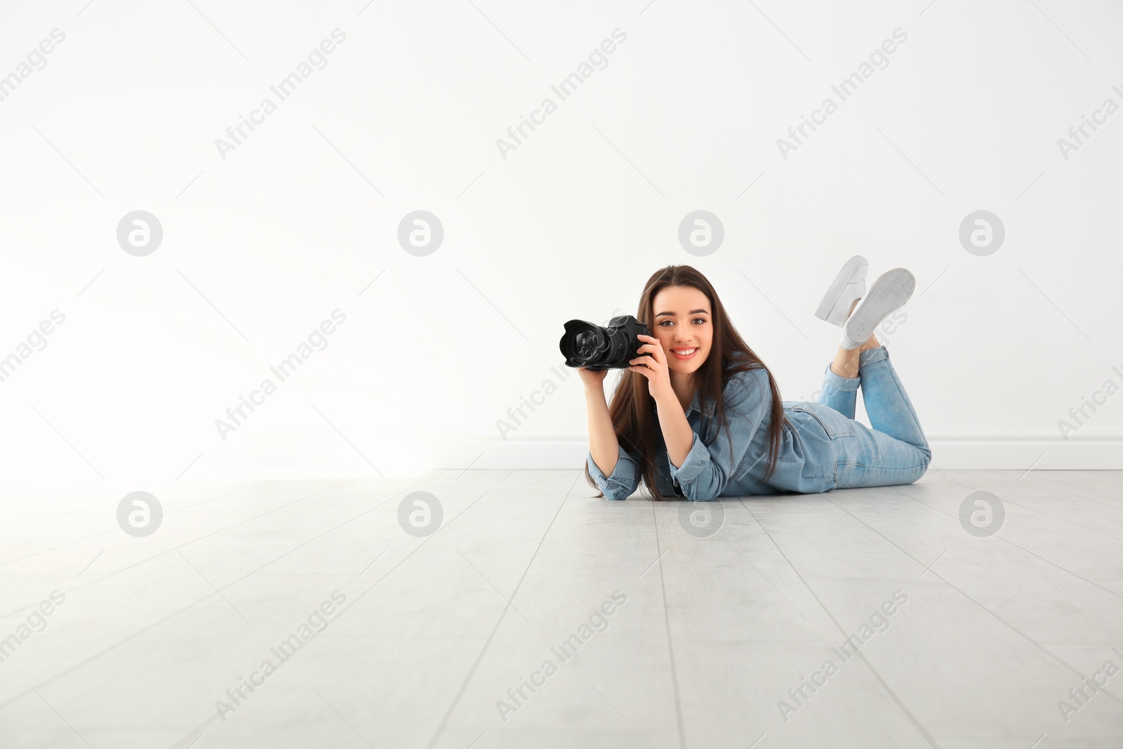 Photo of Female photographer with camera lying on floor indoors