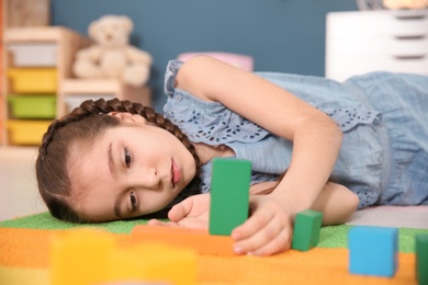 Little autistic girl playing with cubes at home