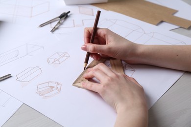 Photo of Woman creating packaging design at light wooden table, closeup