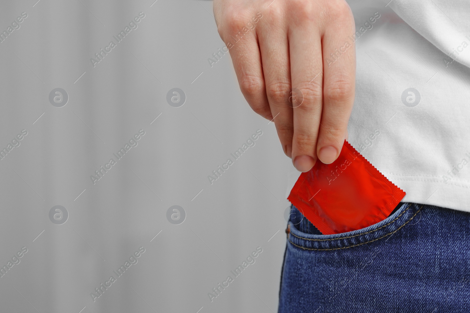Photo of Woman pulling condom out of pocket indoors, closeup and space for text. Safe sex