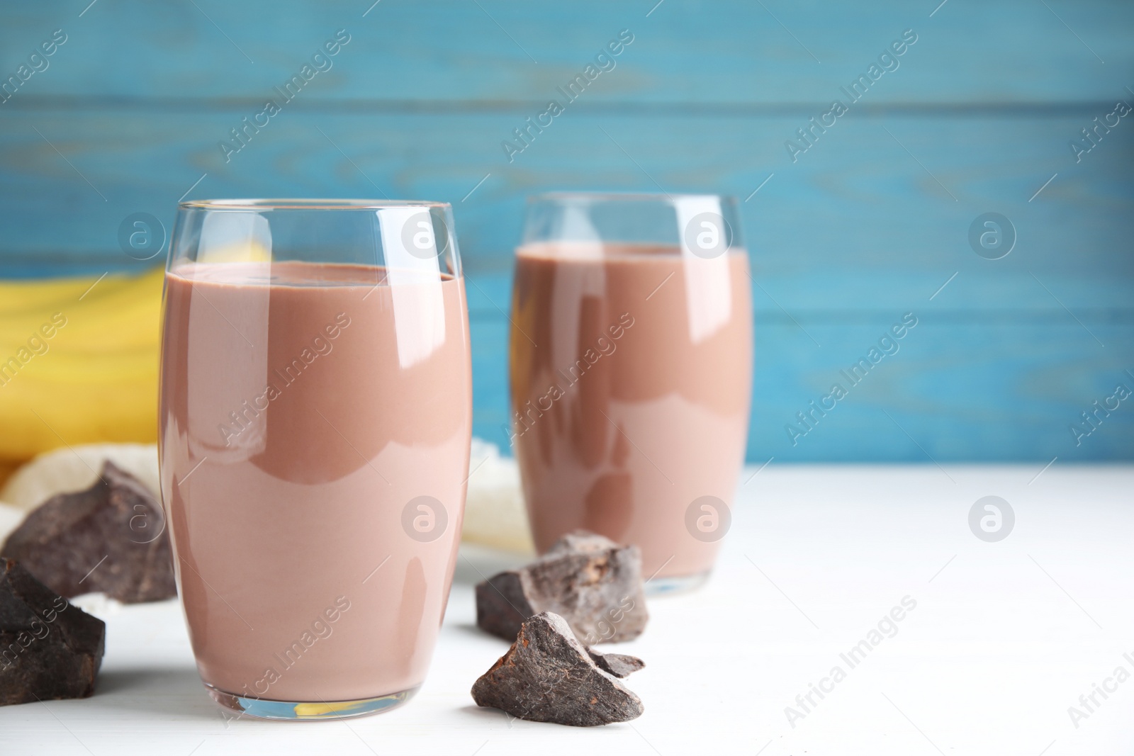 Photo of Fresh yummy chocolate milk on white table. Space for text