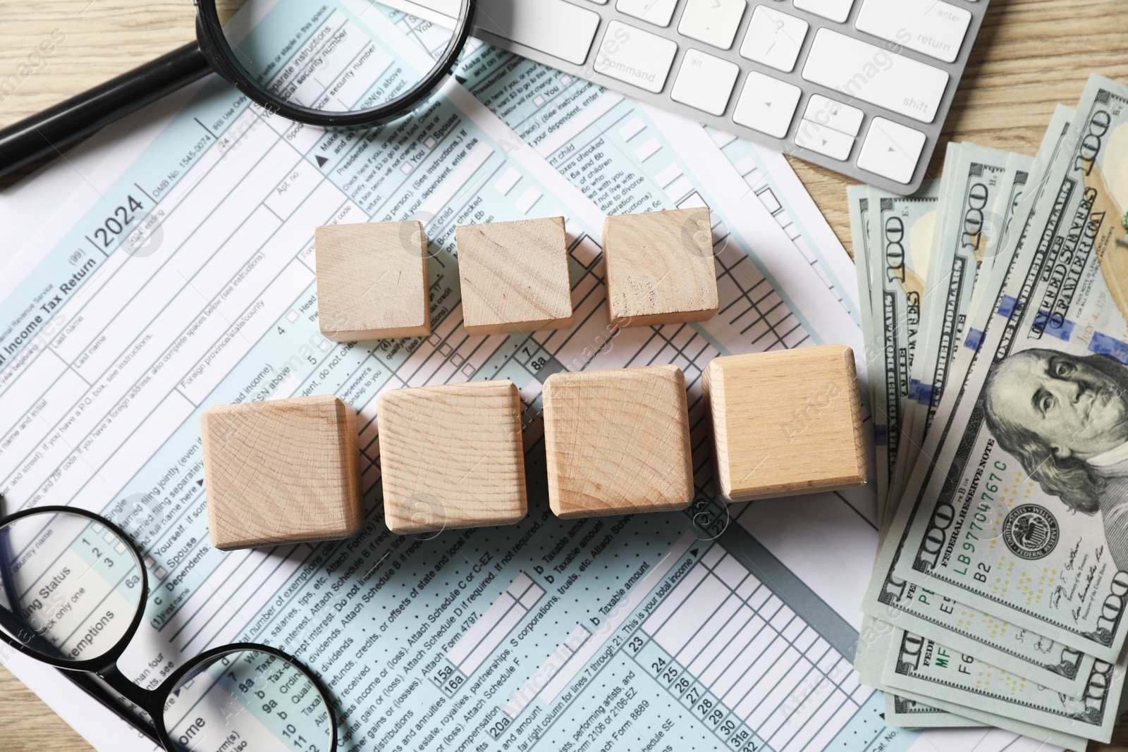 Photo of Taxes. Cubes, money, glasses and documents on light wooden table, flat lay