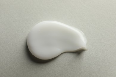 Sample of face cream on light background, top view