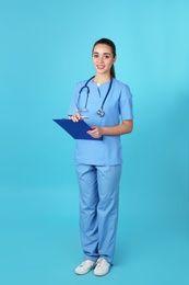 Photo of Young medical student with clipboard on color background
